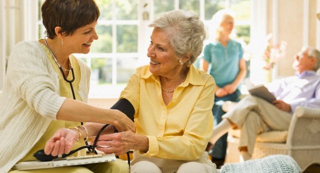 USA, New York State, Old Westbury, Nurse taking pulse of senior woman in nursing home
