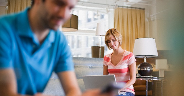 Woman Using Laptop While Boyfriend Uses Cell Phone