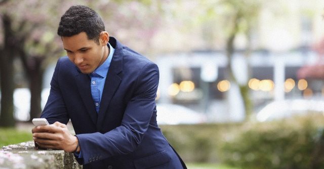 Man in suit using cell phone in urban park