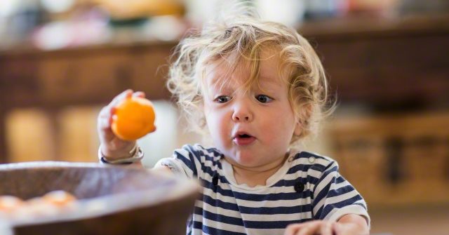 Surprised Caucasian baby boy examining fruit shock children