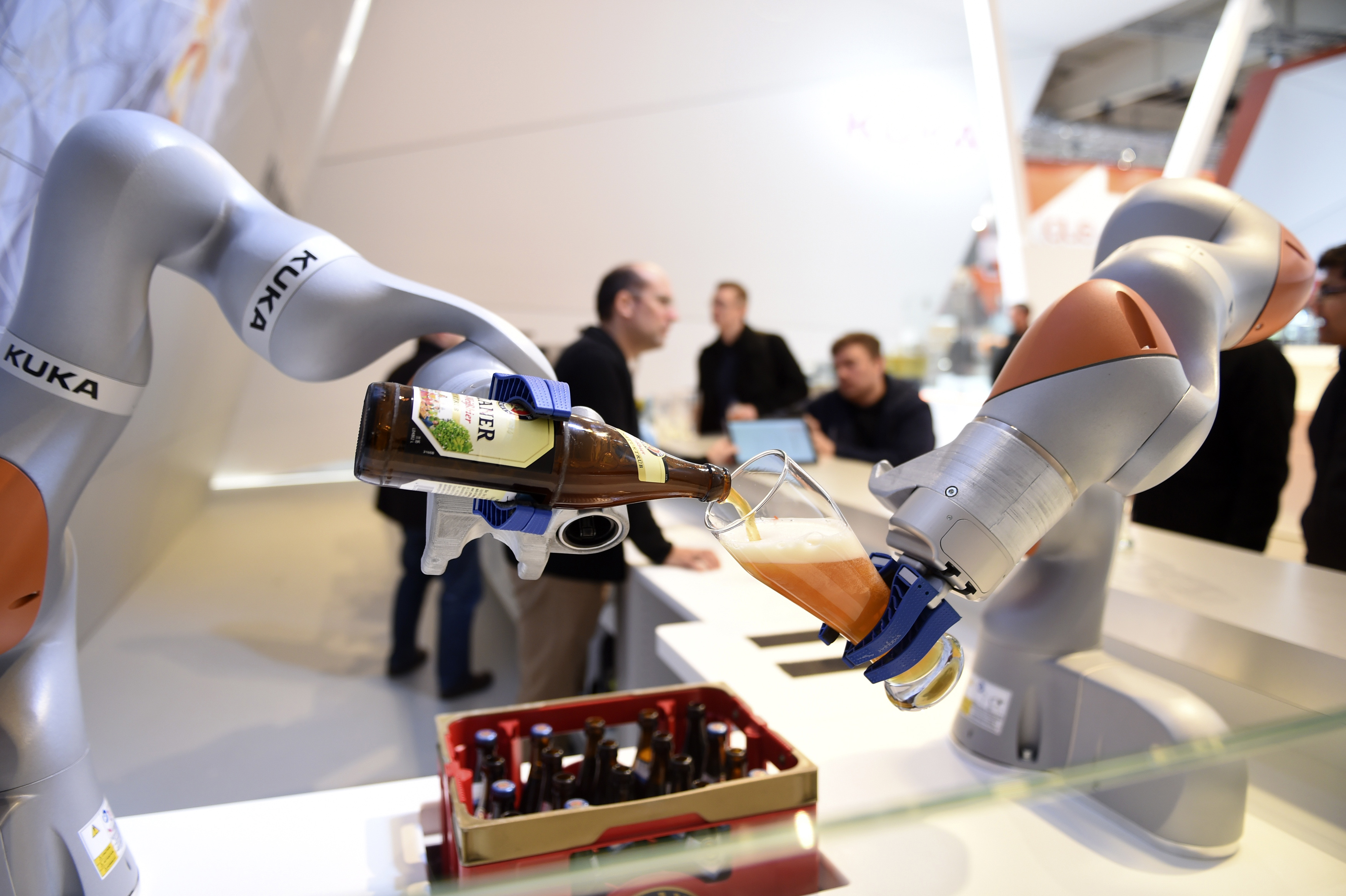 Robots in the Kuka stand pour a beer into a glass at the Hannover Messe industrial trade fair in Hanover