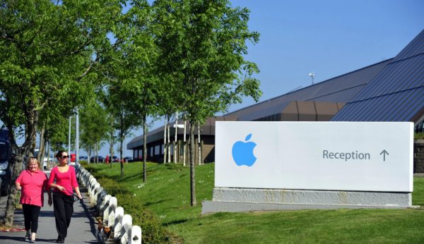 Pedestrians walk with a dog near Apple Inc.